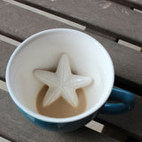 A blue coffee cup with a 3D starfish design, with a portion of the cup filled with a brown beverage. thumbnail