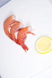 Headless royal red shrimp next to round slice of lemon thumbnail