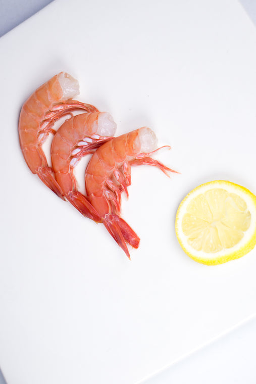 Headless royal red shrimp next to round slice of lemon