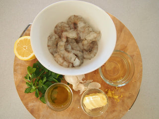 Peeled White shrimp in bowl on top of round cutting board 
