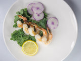 Peeled brown shrimp on top of kale with side of lemon and radish thumbnail