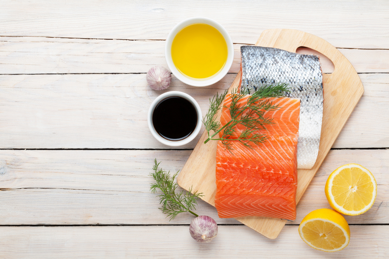 Salmon fillets on cutting board with lemons herbs and drawn butter.