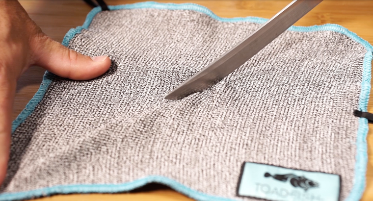 Knife sliding across cut-proof oyster shucking cloth 